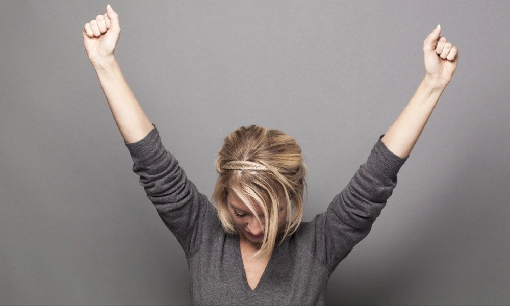 خانمی جوان که دستانش را به نشانه موفقیت مشت کرده است | افزایش عزت نفس