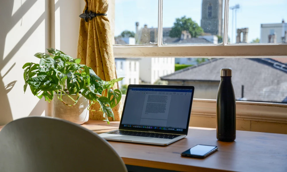 میز کاری که یک لپ تاپ روی آن قرار دارد | فضای کار در خانه