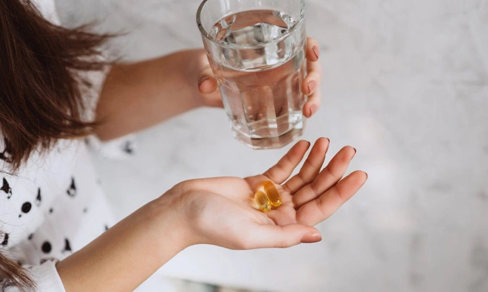 قرص های ویتامین دی در دست یک خانم | علائم کمبود ویتامین دی