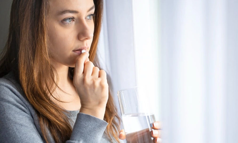 عوارض فلوکستین | خانمی در حال خوردن قرص