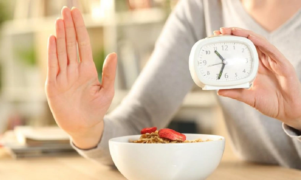 فواید رژیم فستینگ | خانمی که یک ساعت رومیزی کوچک را در دستش گرفته است